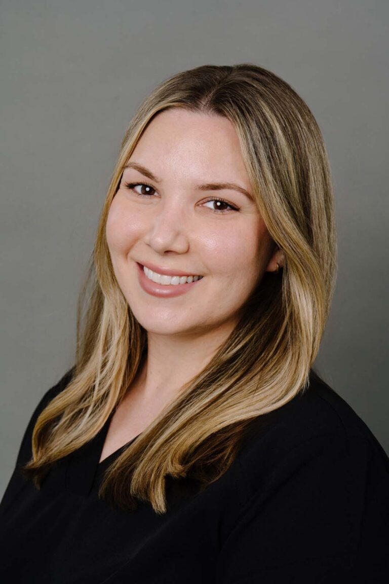 Headshot of a dentist from Missouri City Dentistry wearing a black scrubs. The background is a plain gray color.