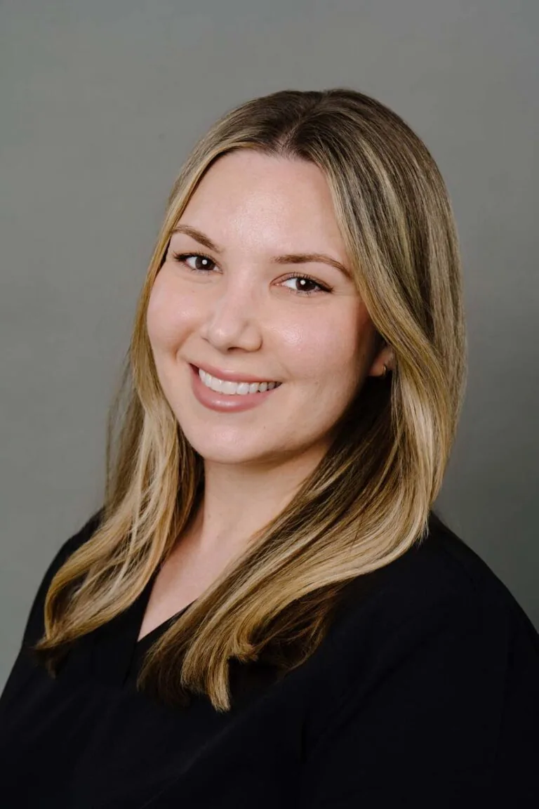 Headshot of a dentist from Missouri City Dentistry wearing a black scrubs. The background is a plain gray color.