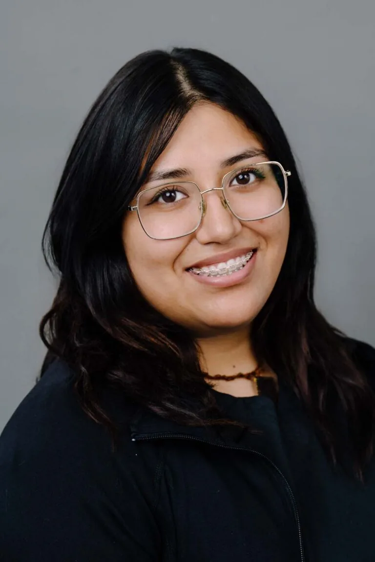 Head shot of a dentist from Missouri City Dentistry wearing a black scrubs and eye glasses. The background is a plain gray color.